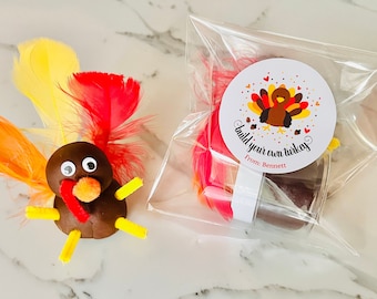 May include: A clear plastic bag filled with brown play dough and colorful feathers. A sticker on the bag reads "Build your own turkey" with a cartoon turkey illustration and the text "From: Bennett".