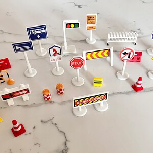 May include: A collection of miniature road signs and traffic cones, including signs for 'Keep Space 50m', 'Stop', 'Road Closed', 'No Entry', and 'Bus Lane'.