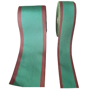 May include: Two spools of green and maroon ribbon. The ribbon is flat and has a woven texture.