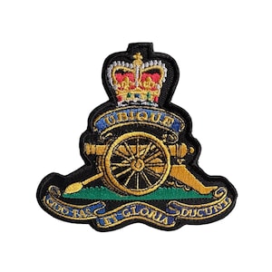 May include: Embroidered patch featuring a gold cannon, a crown, and the words "Ubique" and "Quo Fas Et Gloria Ducunt" on a black background. The patch has a green and blue accent.