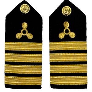 Puede incluir: Un par de hombreras militares negras y doradas con cuatro galones dorados y un insignia de hélice dorada.