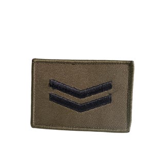 Op de afbeelding: Olijfgroene militaire patch met twee zwarte chevrons. De rechthoekige patch heeft een gestikte rand. Dit insigne wordt vaak gebruikt om rang of dienst aan te duiden.