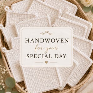 May include: A woven basket filled with white, square handwoven items, each with a loop. The items are arranged around a sign that reads "Handwoven for your Special Day". The basket is surrounded by flowers and greenery.