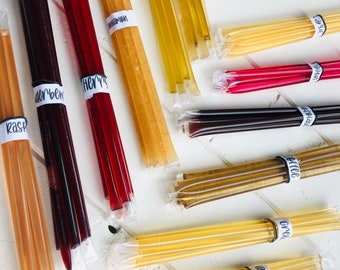 May include: A variety of honey sticks in clear plastic packaging. The honey sticks are labeled with different flavors, including Raspberry, Coffee, Vanilla, and Grape.