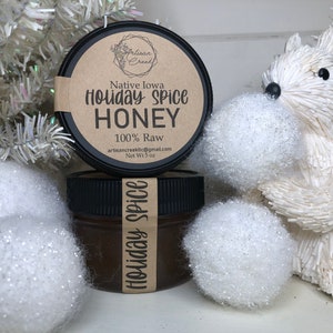Peut inclure: Un pot en verre avec un couvercle noir rempli de miel. L'étiquette sur le pot indique "Native Iowa Holiday Spice Honey 100% Raw artisancreeklic@gmail.com Net Wt 5 oz".