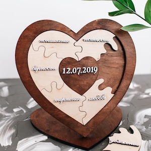 Peut inclure: Un puzzle en bois en forme de cœur composé de six pièces. Chaque pièce porte un mot différent écrit en lettres blanches : "amour", "patience", "confiance", "loyauté", "respect" et "compréhension". La date "12.07.2019" est inscrite au centre du puzzle.