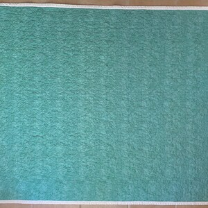 Op de afbeelding: Een tealblauwe quilted stof met een witte rand.
