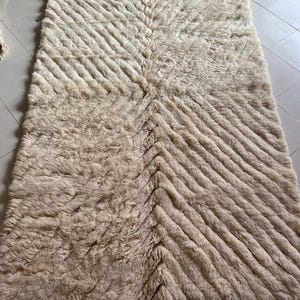 May include: A cream-colored rug with a chevron pattern. The rug is made of a soft, fluffy material.