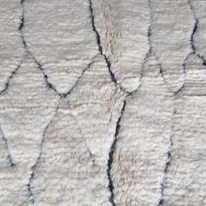 May include: A white rug with a geometric pattern in black. The rug has a soft, fluffy texture.