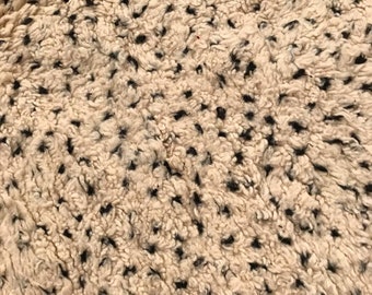 May include: Close-up of a beige and black patterned rug with a soft, fluffy texture.