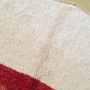May include: A white and red striped rug with a shaggy texture. The rug has a diagonal stripe pattern.