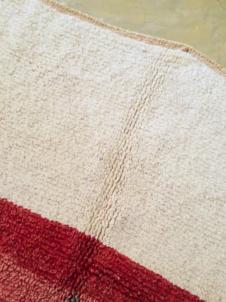 May include: A white and red striped rug with a shaggy texture. The rug has a diagonal stripe pattern.
