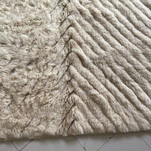 May include: A cream-colored rug with a chevron pattern. The rug is made of a soft, fluffy material.