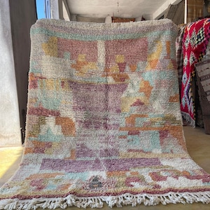 May include: A colorful Moroccan rug with a geometric pattern in shades of pink, orange, yellow, and blue. The rug has a fringe border and is made of wool.