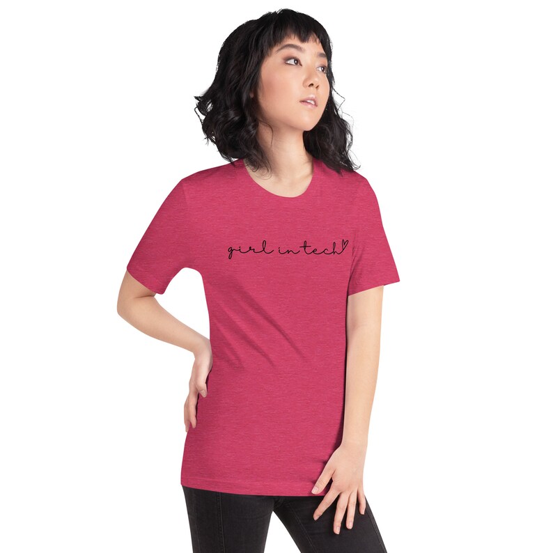 May include: A pink heather t-shirt with the text "girl in tech" in black script with a small heart symbol.