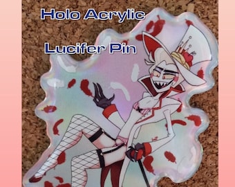 May include: Holographic acrylic pin featuring a cartoon character with white hair, red eyes, and a white and red outfit. The character is holding a cane and has a crown on their head. The background is a white and red holographic design. The text "Lucifer Pin" is written above the character.
