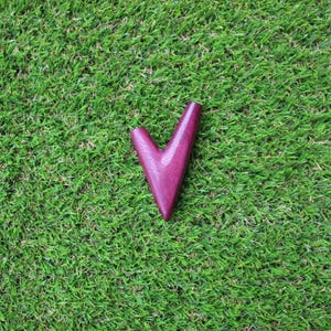 May include: A deep purple wooden pipe shaped like a V, sitting on a green grassy surface.