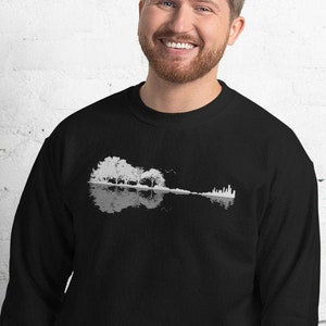 May include: A black sweatshirt featuring a white graphic of a guitar silhouette formed from trees and a reflection in water.
