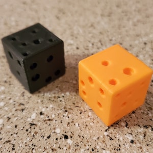 May include: Two dice, one black and one orange, with holes drilled into each side.