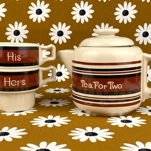 May include: A brown and white striped teapot with the text "Tea For Two" and two stacked brown and white striped mugs with the text "His" and "Hers".