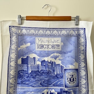May include: A white tea towel with a blue border and a blue image of a castle with the text "Malingware Ringtons" in the centre.