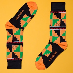 May include: A pair of orange, green, and black socks with a geometric pattern. The socks have the text "54 KINGDOMS" and "54 KINGDOMS" on them.