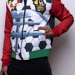 May include: A white, red, and green bomber jacket with a soccer ball pattern. The jacket has a zipper closure and a patch on the left side that says "Forward Ever Backward Never".