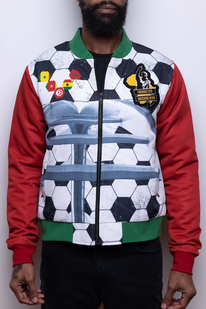 May include: A white bomber jacket with a soccer ball pattern and red and green sleeves. The jacket has a zipper closure and a patch on the chest that says "Forward Ever Backward Never".