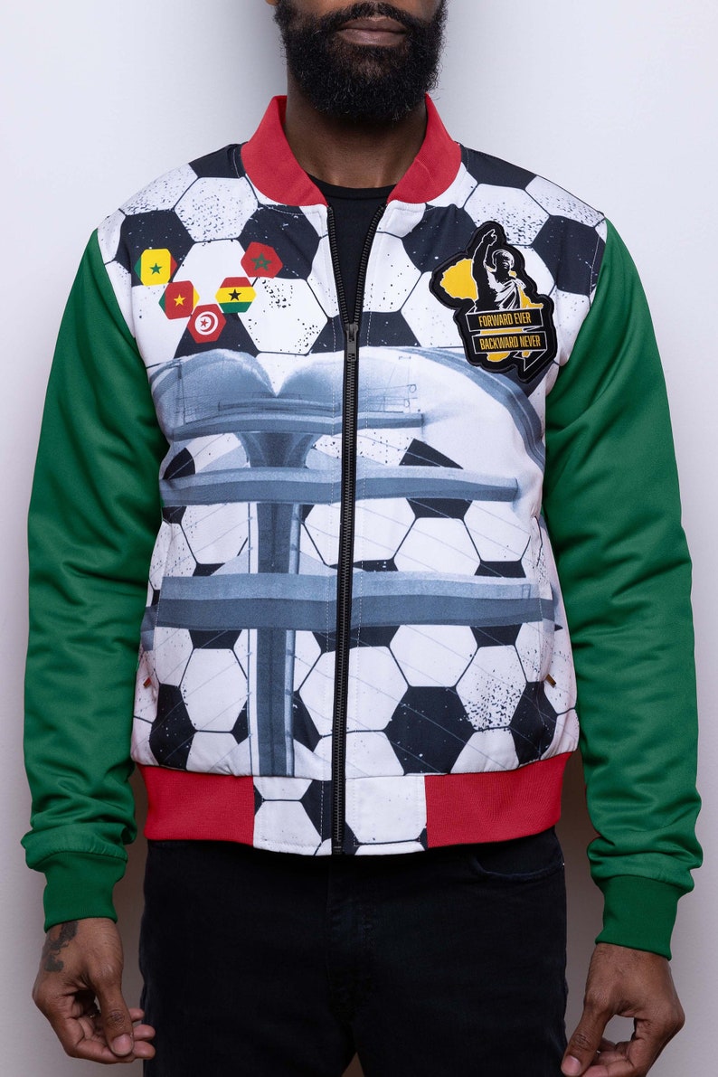 May include: A white, red, and green bomber jacket with a soccer ball pattern. The jacket has a zipper closure and a patch on the right side that says "Forward Ever Backward Never".
