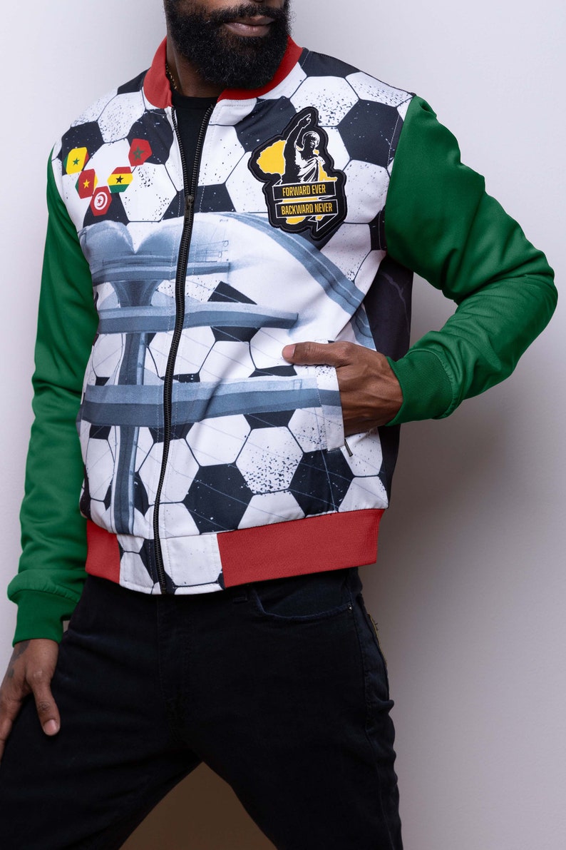 May include: A white, green, and red bomber jacket with a soccer ball pattern and a patch that says "Forward Ever Backward Never".