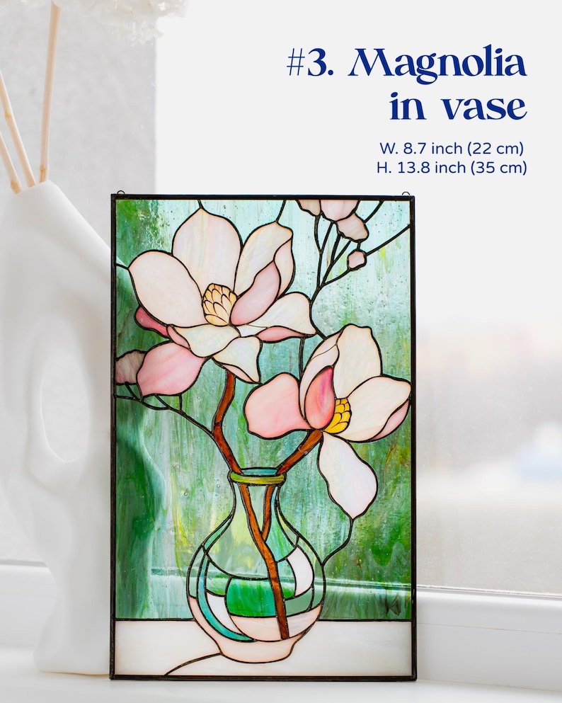Puede incluir: Panel de vidriera con una magnolia en un jarr&oacute;n. La obra presenta un fondo verde y blanco con flores de magnolia rosas y blancas. El panel mide 22 cm de ancho y 35 cm de alto.