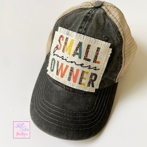 May include: Black and beige trucker hat with a patch that says "SMALL business OWNER" in colorful letters with a leopard print pattern.