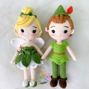 Könnte beinhalten: Gehäkelte Amigurumi-Puppen von Tinkerbell und Peter Pan. Tinkerbell trägt ein grünes Kleid mit weißen Flügeln und hat gelbes Haar. Peter Pan trägt einen grünen Hut, ein grünes Hemd und eine grüne Hose mit braunen Stiefeln.