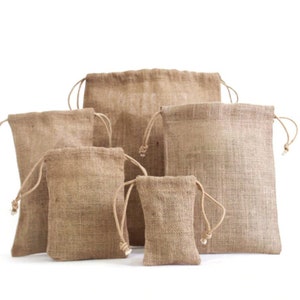 Può includere: Una collezione di sacchetti con coulisse in iuta di varie dimensioni. Le borse sono di colore marrone naturale, con una trama intrecciata. Ogni borsa ha una chiusura con coulisse abbinata nella parte superiore.