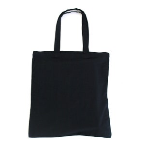 May include: A solid black tote bag with two matching handles. The bag is rectangular and made of a soft, opaque material. The handles are attached at the top of the bag and are designed for carrying over the shoulder or by hand.