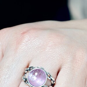 May include: A silver ring featuring a pink gemstone set within a chain-link design.