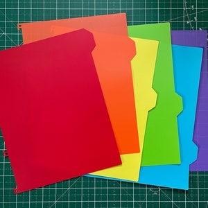 May include: A set of six colourful file folders, arranged in a rainbow pattern from red to purple. The folders are made of sturdy cardstock and have a tabbed design for easy organisation.