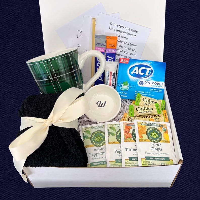 Peut inclure: Un coffret cadeau contenant une tasse &agrave; carreaux verts, un petit bol blanc avec un "W", des chaussettes noires nou&eacute;es avec un ruban cr&egrave;me, des sachets de th&eacute;, des pastilles et des bonbons au gingembre. La bo&icirc;te contient une note avec du texte.