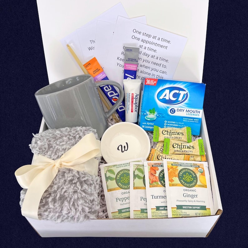 Peut inclure: Un coffret cadeau rempli d'articles de soins personnels. Comprend une tasse grise, un petit bol avec un "w", une couverture grise et floue attach&eacute;e avec un ruban cr&egrave;me, des sachets de th&eacute;, des pastilles et un tube d'Aquaphor. Le coffret contient &eacute;galement de petits mots encourageants.