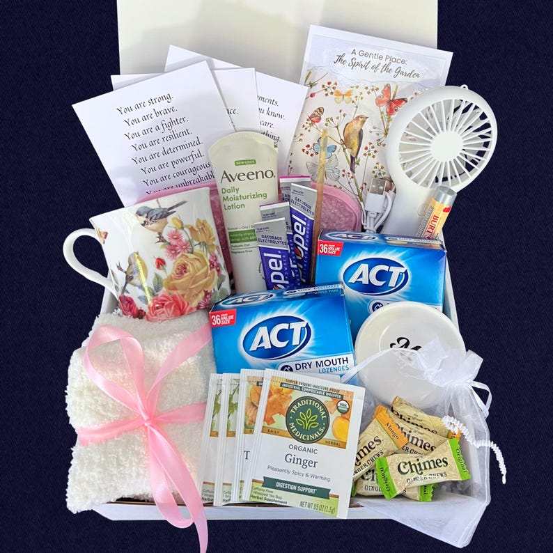 Puede incluir: Una caja de regalo llena de art&iacute;culos de cuidado personal. Incluye una taza floral, loci&oacute;n Aveeno, pastillas para la boca seca ACT, t&eacute; de jengibre, un ventilador peque&ntilde;o y un pa&ntilde;o blanco atado con una cinta rosa. Se incluyen citas inspiradoras.