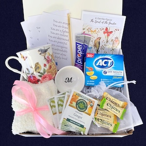 Puede incluir: Una caja de regalo llena de art&iacute;culos de cuidado personal. Incluye una taza de t&eacute; floral, un cuenco blanco peque&ntilde;o con la letra "M", bolsitas de t&eacute;, pastillas, caramelos de jengibre, un pa&ntilde;o con una cinta rosa y tarjetas inspiradoras.