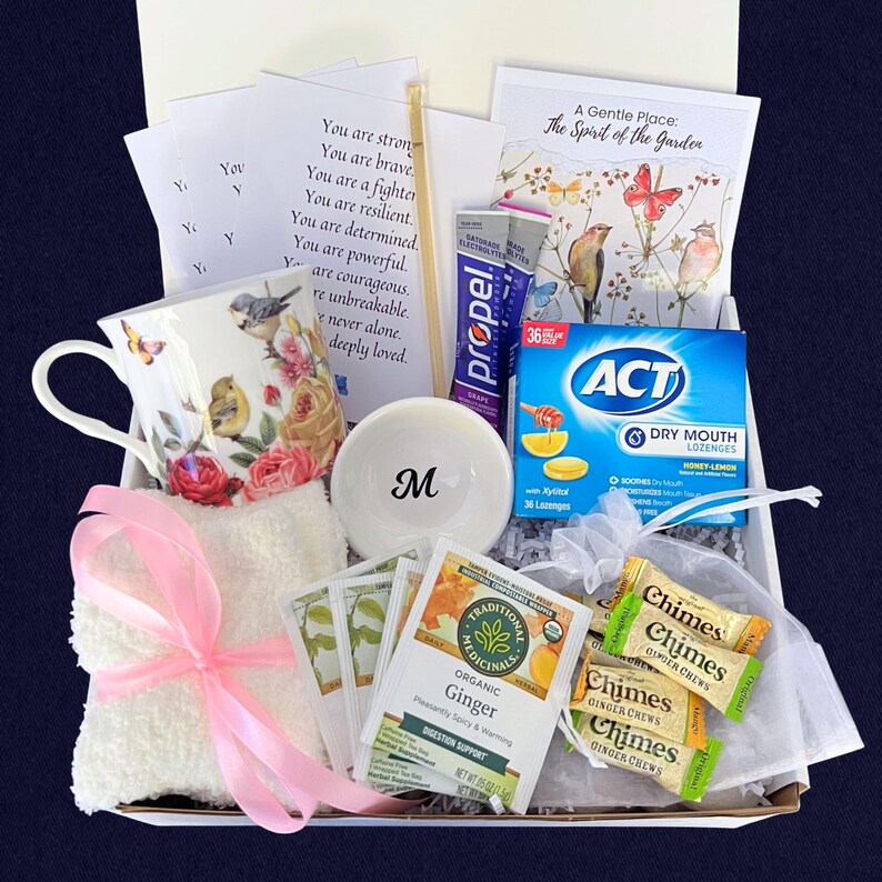 Puede incluir: Una caja de regalo llena de art&iacute;culos de cuidado personal. Incluye una taza de t&eacute; floral, un cuenco blanco peque&ntilde;o con la letra "M", bolsitas de t&eacute;, pastillas, caramelos de jengibre, un pa&ntilde;o con una cinta rosa y tarjetas inspiradoras.