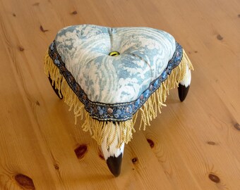 Elegant upholstered monster stool with dragon eye button and horn legs, unique decor item