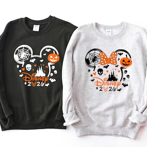 May include: A black sweatshirt and a light gray sweatshirt, each featuring a graphic of a Mickey Mouse silhouette filled with Halloween icons including a spider web, a jack-o'-lantern, a skull, bats, and the text Disney 2020 in orange.
