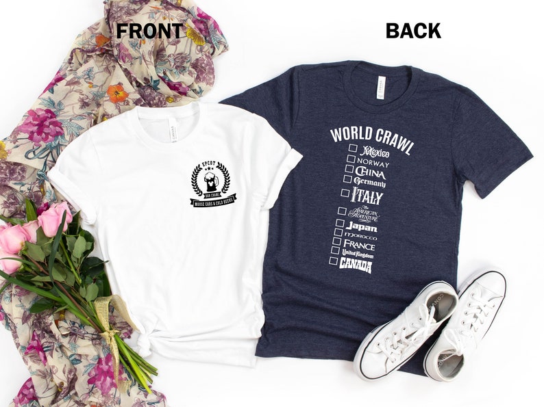 May include: Two t-shirts, one white and one dark blue. The white t-shirt has a black graphic of a beer mug with the text "I've Tried" and "World Crawl & Chill Vibes". The dark blue t-shirt has the text "WORLD CRAWL" and a checklist of countries with checkboxes.