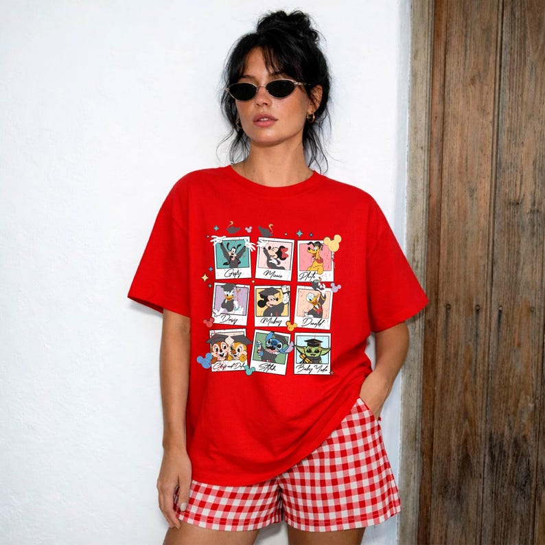 May include: A red t-shirt featuring a grid of nine Disney character portraits. The characters include Goofy, Minnie Mouse, and Donald Duck. The model is wearing red and white checkered shorts.