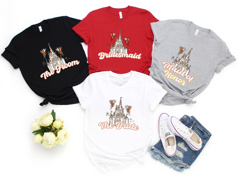May include: Five t-shirts with a graphic of Cinderella's castle and text that reads "The Groom", "Bridemaid", "Maid of Honor", and "The Bride".