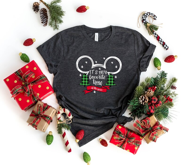 Puede incluir: Una camiseta gris oscuro con una silueta blanca de Mickey Mouse y dos &aacute;rboles de Navidad de cuadros verdes y rojos. El texto "It's my favorite time of the year" est&aacute; impreso en la camiseta.