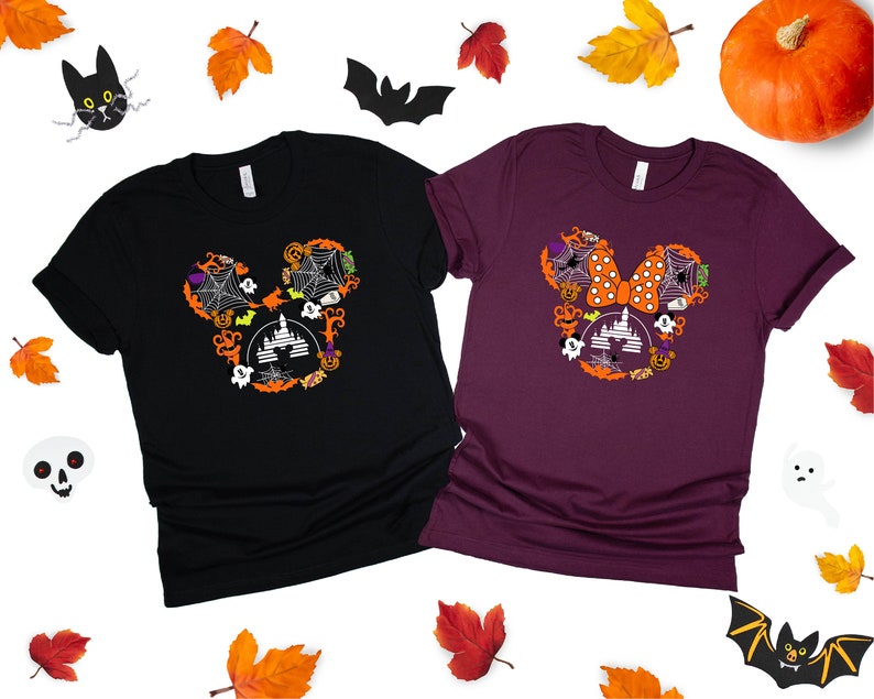 May include: Two t-shirts with a Halloween Mickey Mouse design. The black shirt has a white Mickey Mouse head with a spiderweb, castle, and other Halloween elements. The maroon shirt has a white Mickey Mouse head with a bow, spiderweb, castle, and other Halloween elements.