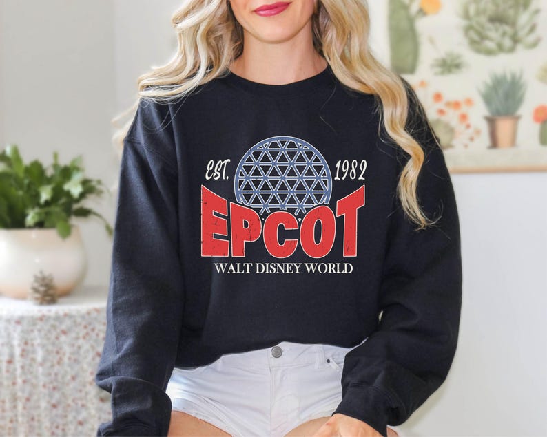 May include: Black sweatshirt with a distressed graphic featuring the word "EPCOT" in red, a blue and white geometric sphere, and the text "Walt Disney World" below. The sweatshirt also includes the text "est. 1982".